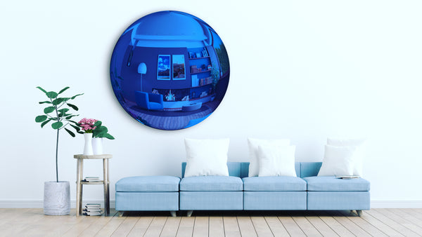 A person standing in a hallway is visible in the reflection of a framed convex mirror.
