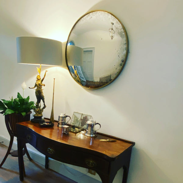 Two convex mirrors with black frames arranged on a textured, light-colored wall.