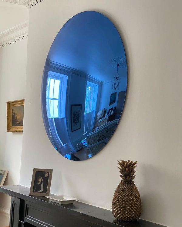 Antique convex mirror hanging above a white fireplace mantel.